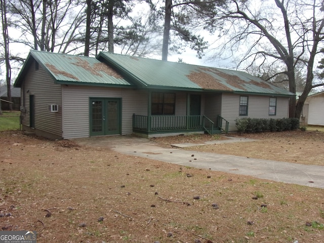 view of front of home featuring french doors, covered porch, and metal roof