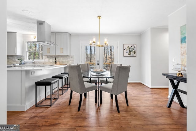 dining space featuring baseboards, a notable chandelier, and wood finished floors