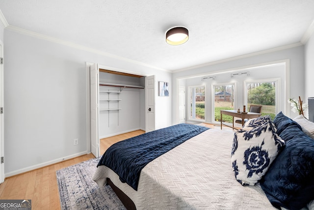 bedroom featuring light wood finished floors, crown molding, baseboards, a closet, and a textured ceiling