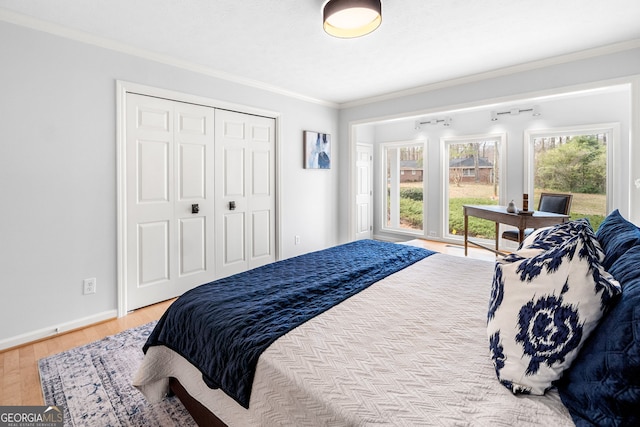 bedroom featuring crown molding, wood finished floors, baseboards, and a closet