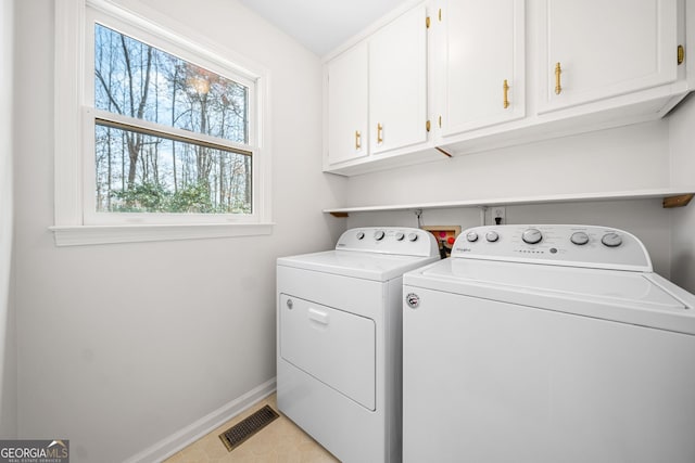 clothes washing area with separate washer and dryer, cabinet space, visible vents, and baseboards