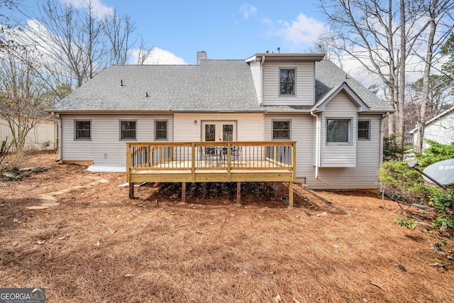 rear view of house with a wooden deck, roof with shingles, a chimney, and french doors