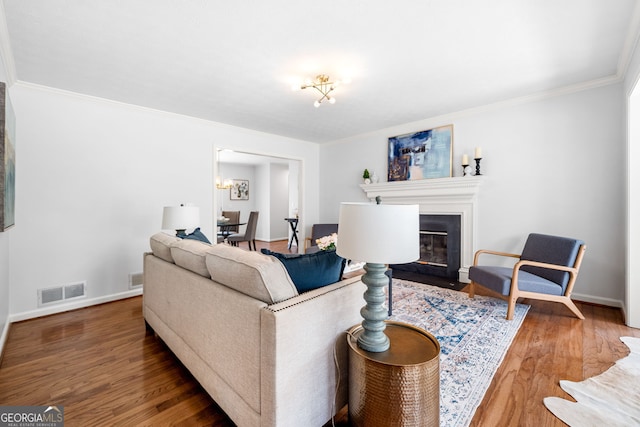 living area with crown molding, wood finished floors, visible vents, and baseboards