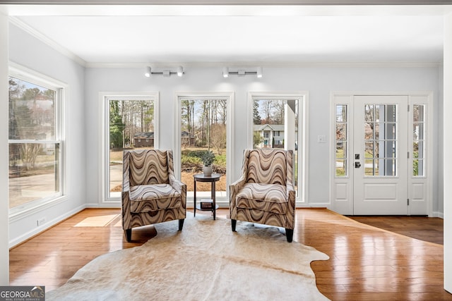 sitting room with hardwood / wood-style flooring, plenty of natural light, crown molding, and baseboards