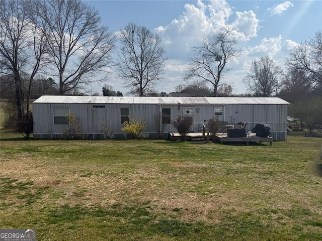 rear view of property featuring a wooden deck and a lawn