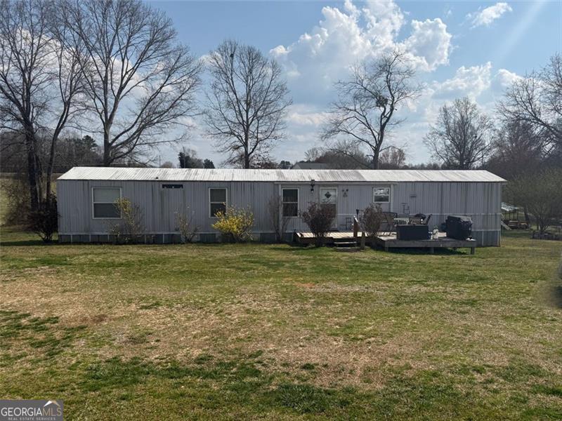 rear view of property with a deck and a lawn