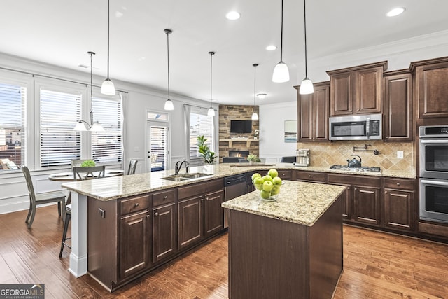 kitchen featuring backsplash, a kitchen island, crown molding, stainless steel appliances, and a sink