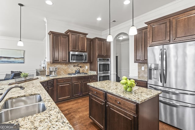 kitchen with arched walkways, a sink, ornamental molding, dark brown cabinetry, and stainless steel appliances