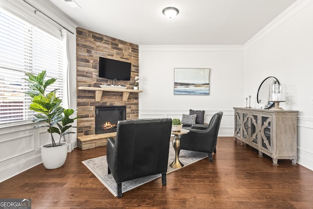 living area with a decorative wall, a fireplace, crown molding, and wood finished floors