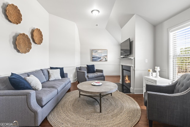 living area with dark wood finished floors, a fireplace with flush hearth, and baseboards