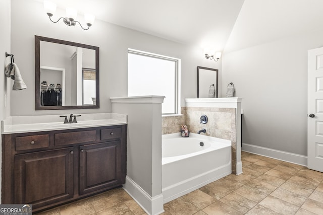 full bathroom with a bath, baseboards, vanity, and lofted ceiling