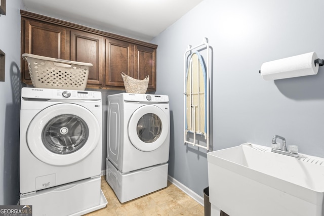 washroom with a sink, baseboards, cabinet space, and washing machine and clothes dryer