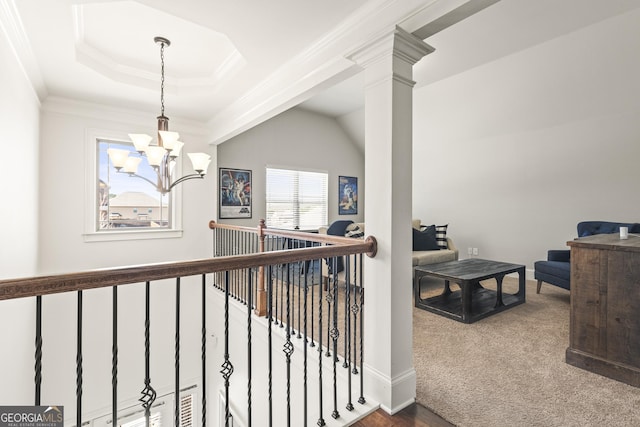 corridor featuring an upstairs landing, ornamental molding, carpet flooring, a raised ceiling, and a chandelier