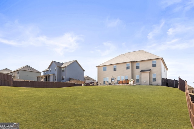 rear view of house featuring a lawn and fence