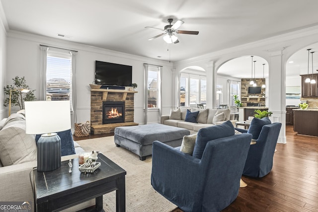 living room with visible vents, dark wood-type flooring, arched walkways, crown molding, and ceiling fan