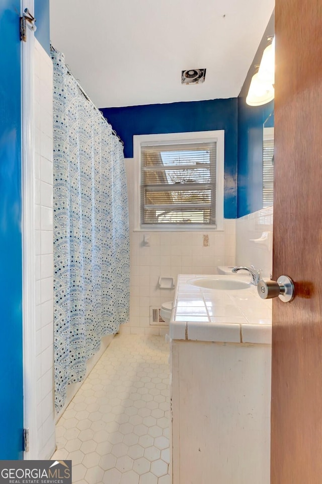 full bathroom with vanity, a shower with curtain, visible vents, tile walls, and tile patterned floors