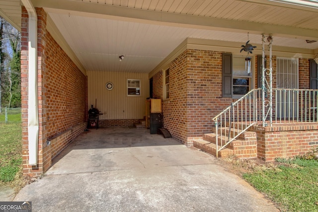 entrance to property featuring a carport, a porch, brick siding, and driveway