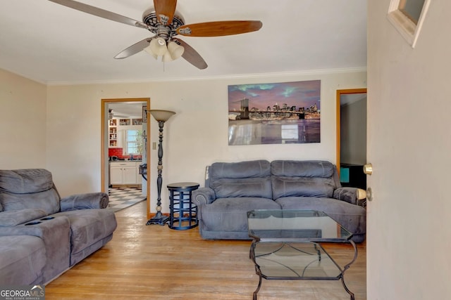 living room with wood finished floors, ceiling fan, and ornamental molding