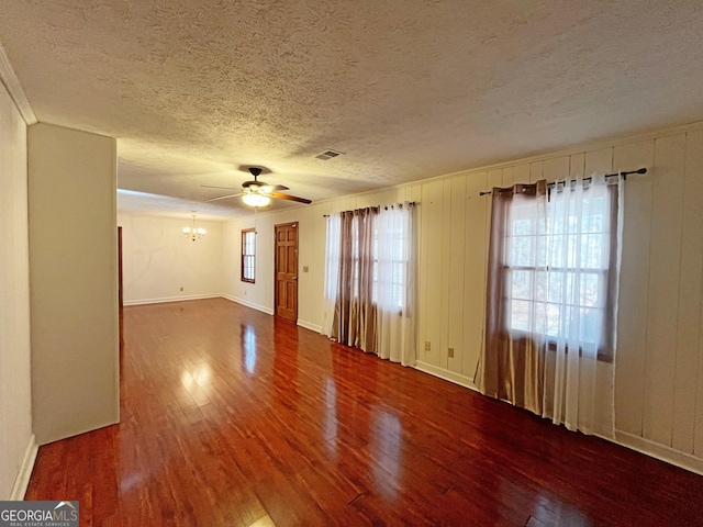 spare room with visible vents, baseboards, ceiling fan with notable chandelier, wood finished floors, and a textured ceiling