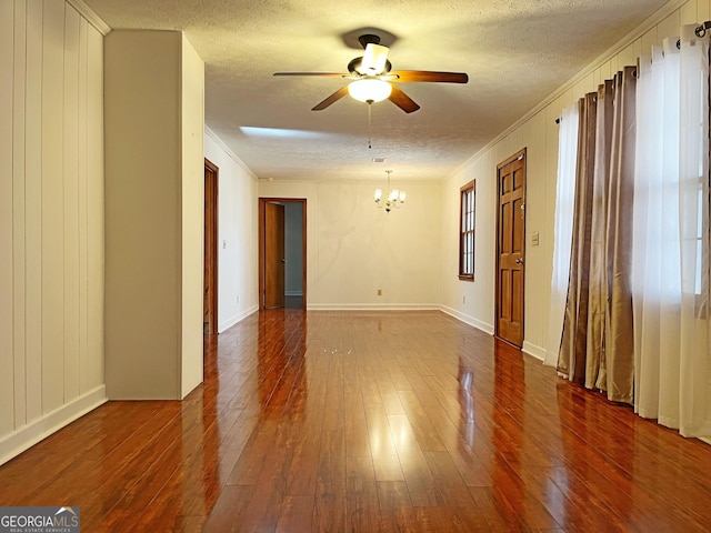 unfurnished room with crown molding, baseboards, ceiling fan with notable chandelier, dark wood-style floors, and a textured ceiling