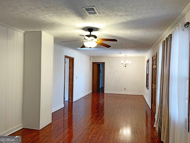 spare room with visible vents, ornamental molding, dark wood-type flooring, a textured ceiling, and ceiling fan with notable chandelier