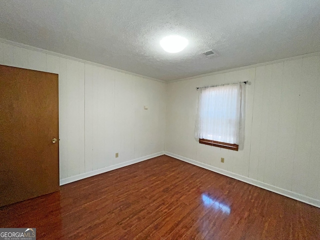 unfurnished room featuring visible vents, a textured ceiling, baseboards, and wood finished floors