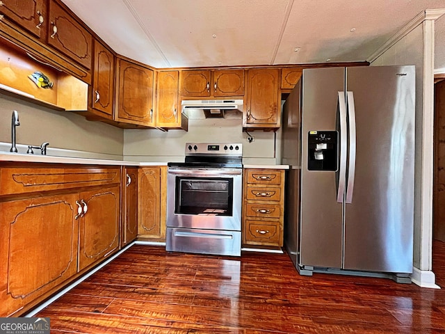 kitchen featuring dark wood finished floors, a sink, under cabinet range hood, appliances with stainless steel finishes, and brown cabinets