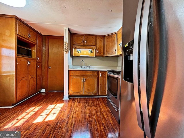 kitchen featuring a sink, brown cabinets, dark wood-type flooring, and appliances with stainless steel finishes