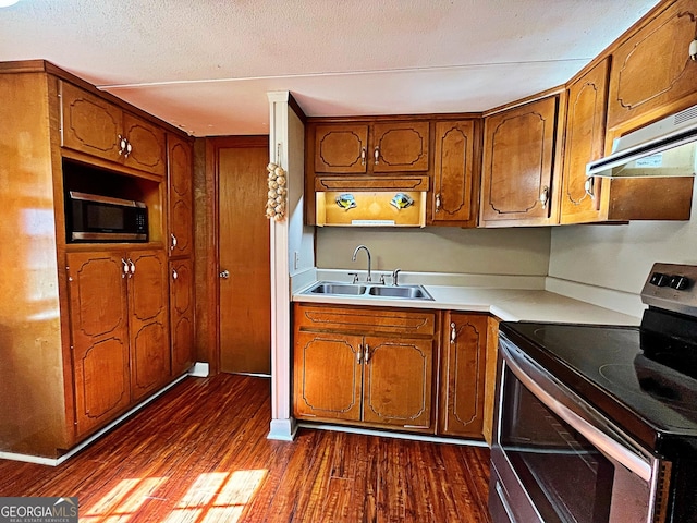 kitchen featuring under cabinet range hood, brown cabinets, appliances with stainless steel finishes, and a sink