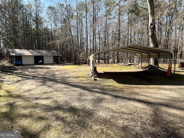 view of yard featuring a carport, an outdoor structure, and dirt driveway