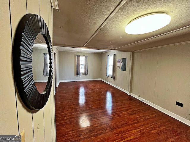 spare room featuring a textured ceiling, baseboards, and wood finished floors