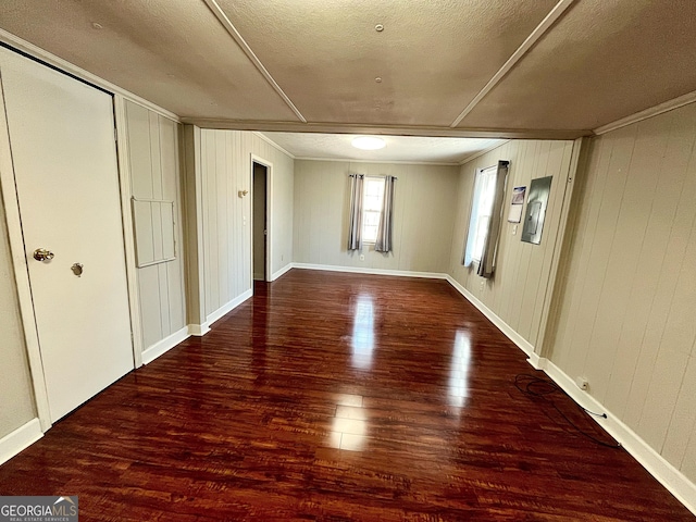 empty room featuring wood finished floors, baseboards, and ornamental molding