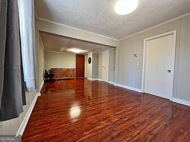 unfurnished living room featuring ornamental molding, a textured ceiling, baseboards, and wood finished floors