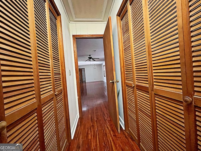 hall featuring a heating unit, crown molding, baseboards, and wood finished floors