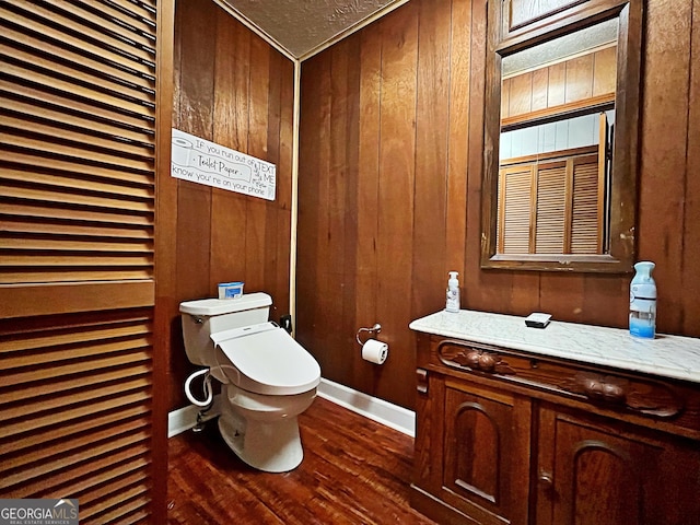 bathroom with wooden walls, toilet, baseboards, and wood finished floors