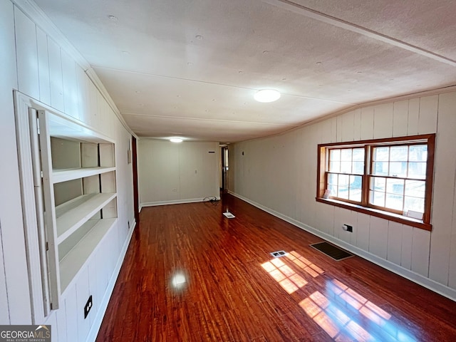 spare room with vaulted ceiling, wood finished floors, visible vents, and a textured ceiling