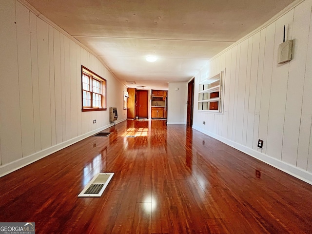 unfurnished living room featuring visible vents, built in shelves, hardwood / wood-style flooring, heating unit, and baseboards