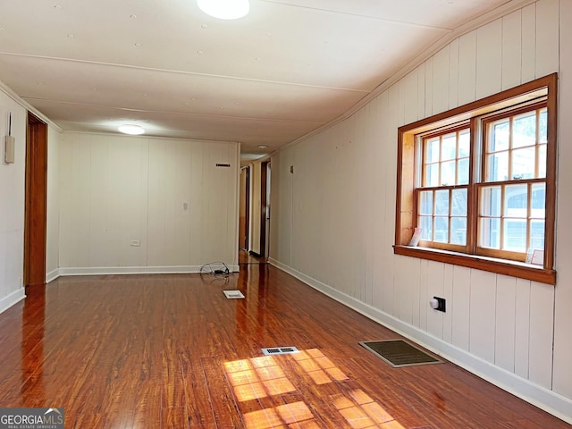 unfurnished room with wood finished floors, visible vents, and baseboards