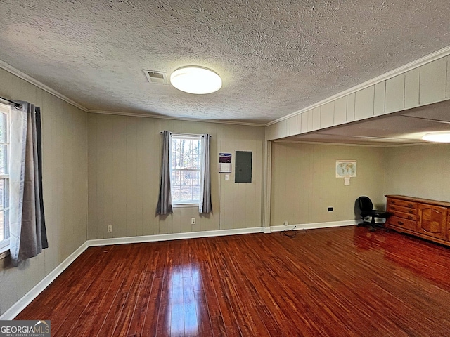 unfurnished room featuring wood finished floors, visible vents, baseboards, electric panel, and crown molding