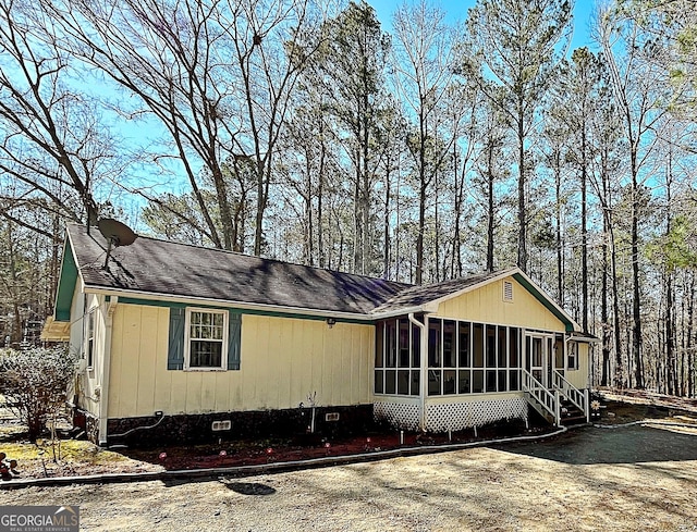 view of front of home with crawl space, a shingled roof, and a sunroom