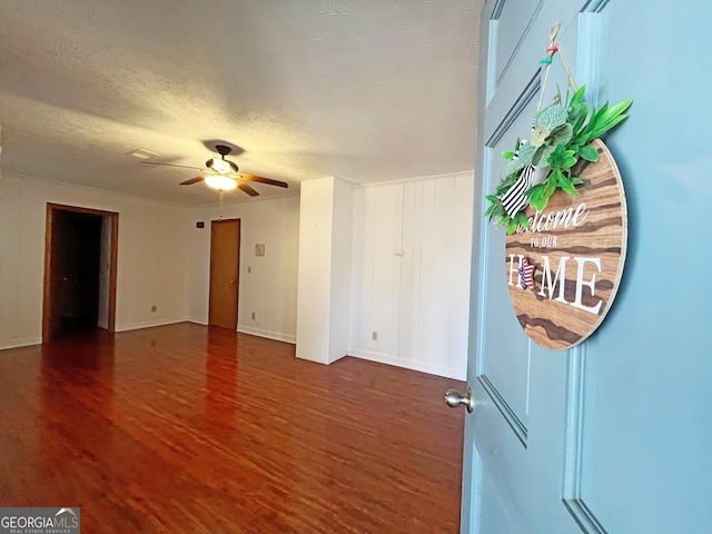 interior space with a ceiling fan, wood finished floors, baseboards, and a textured ceiling