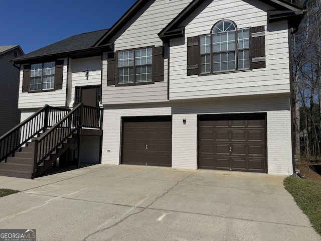 split foyer home with concrete driveway, an attached garage, and brick siding