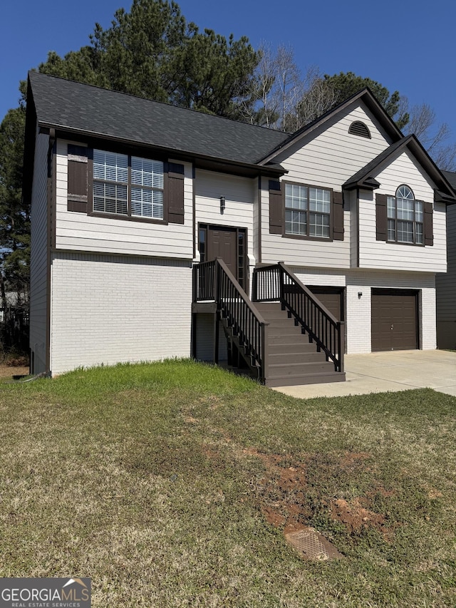 split foyer home with a front lawn, a garage, and brick siding