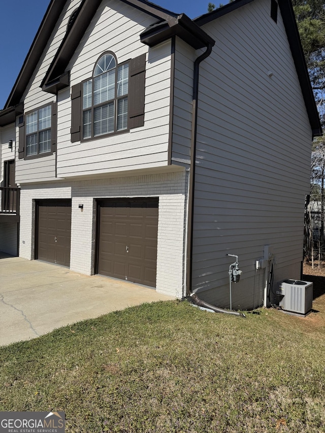 view of side of property featuring brick siding, central AC, a garage, a yard, and driveway