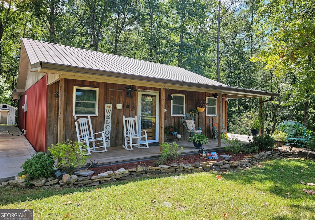 view of front of house featuring a standing seam roof, covered porch, metal roof, and a front yard
