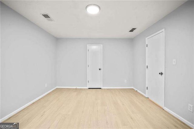 empty room with wood finished floors, visible vents, and baseboards