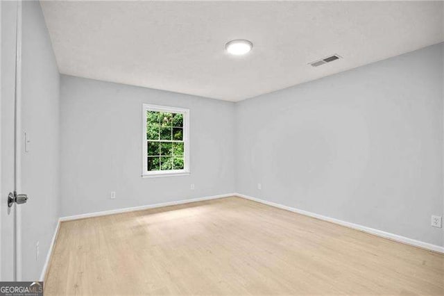 spare room with visible vents, baseboards, and wood finished floors