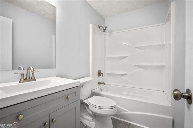 bathroom with vanity, a textured ceiling, washtub / shower combination, and toilet