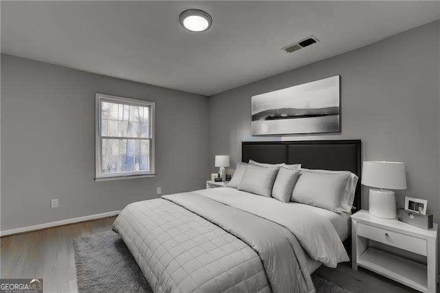 bedroom featuring visible vents, baseboards, and wood finished floors