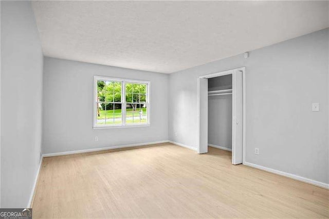 unfurnished bedroom with wood finished floors, baseboards, a closet, and a textured ceiling